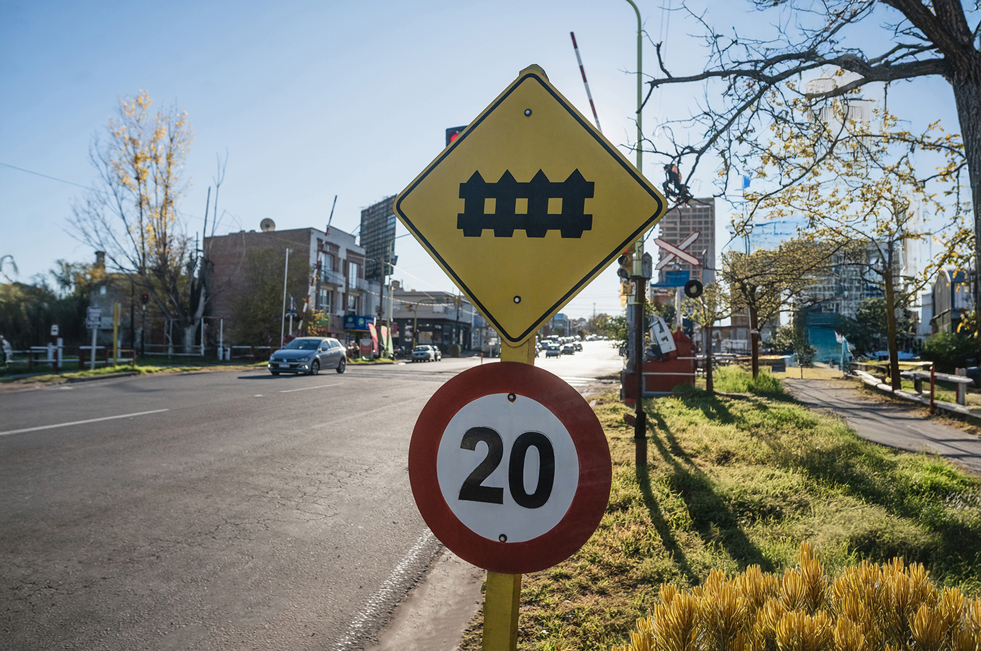 Señal vial de cruce ferroviario y límite de velocidad de 20 km/h en un paso a nivel urbano.