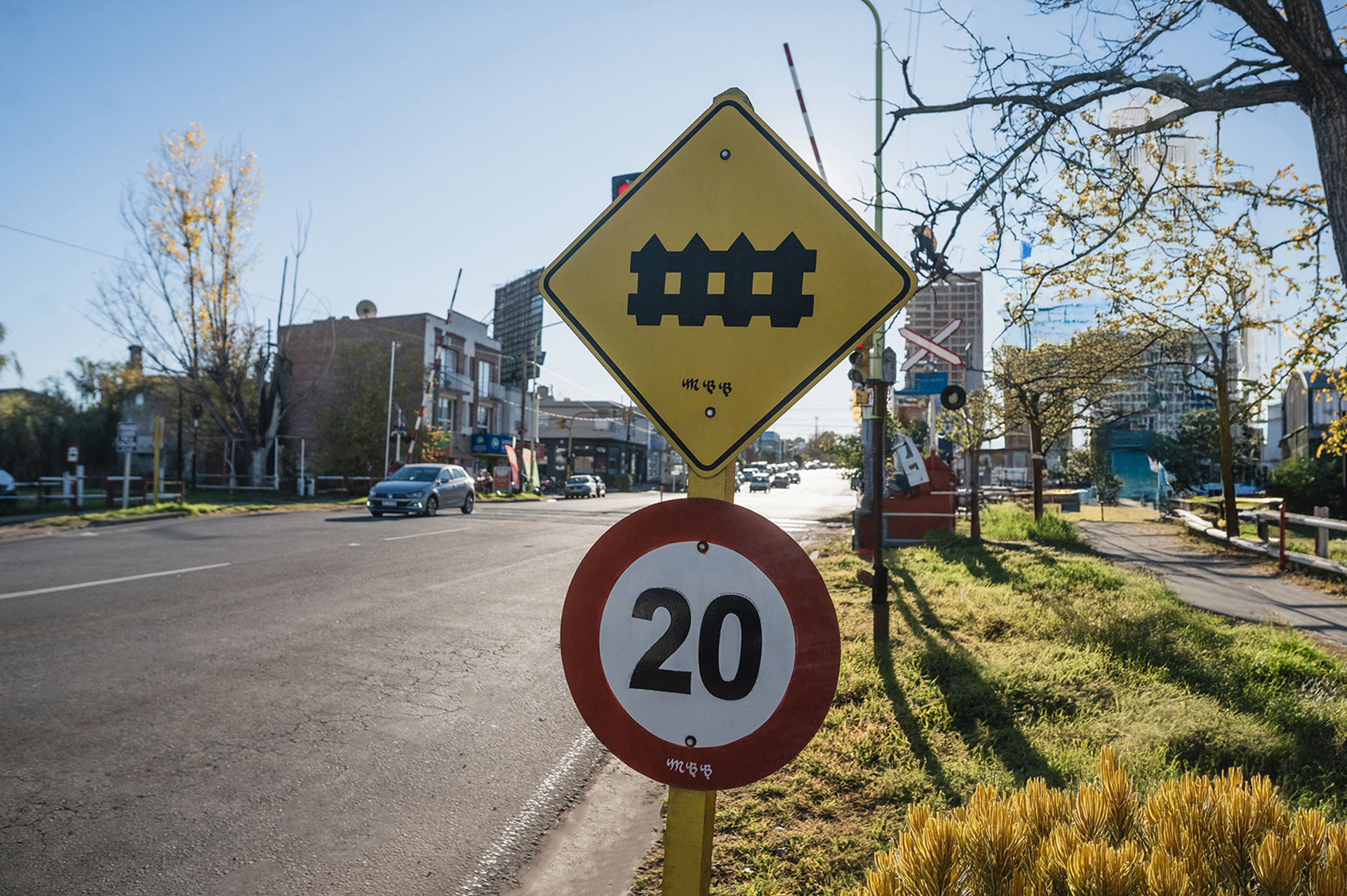 Cartel de cruce ferroviario y señal de velocidad máxima 20 km/h en zona urbana.
