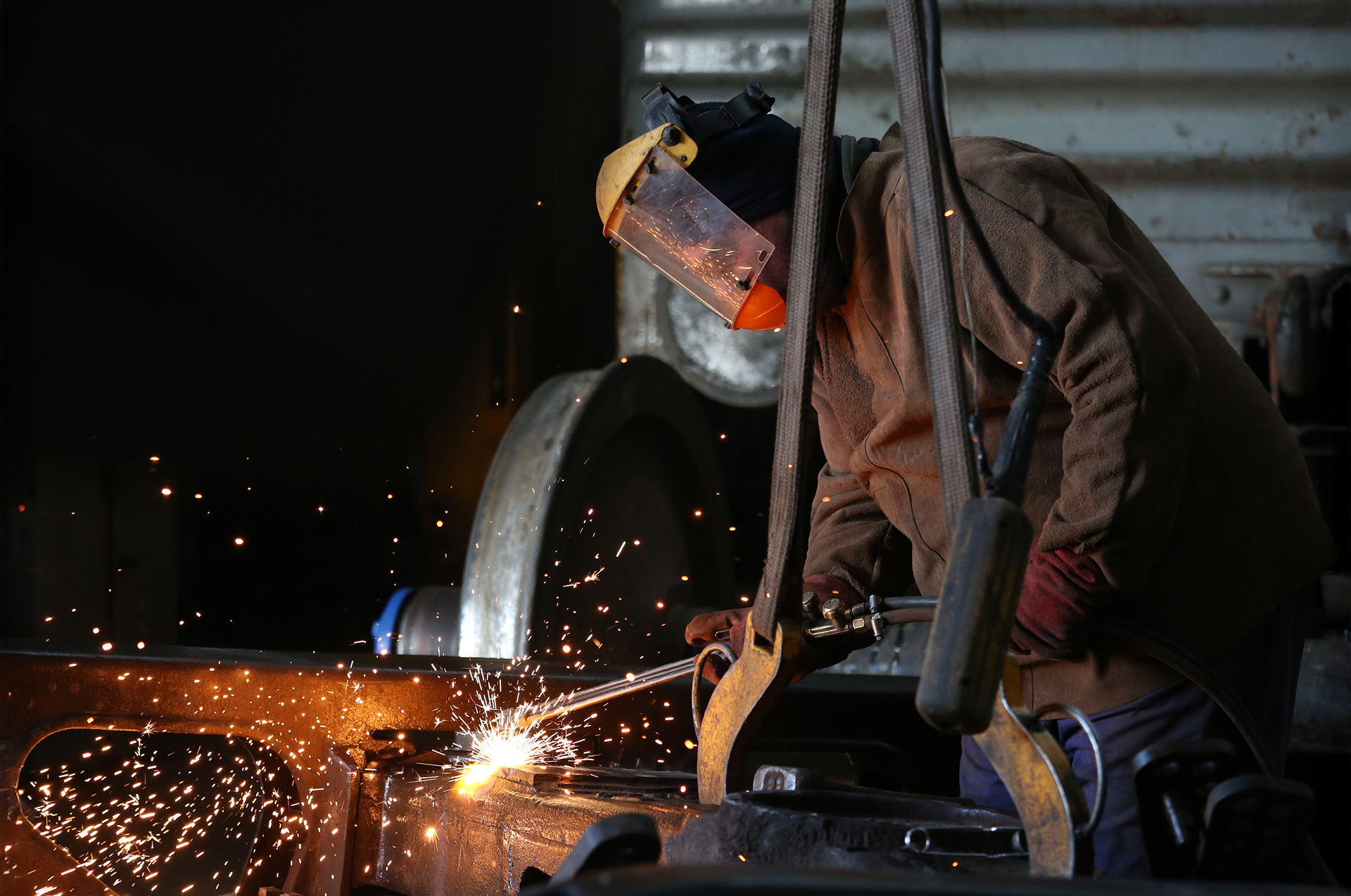 Imagen de trabajador ferroviario soldando piezas metálicas con máscara protectora