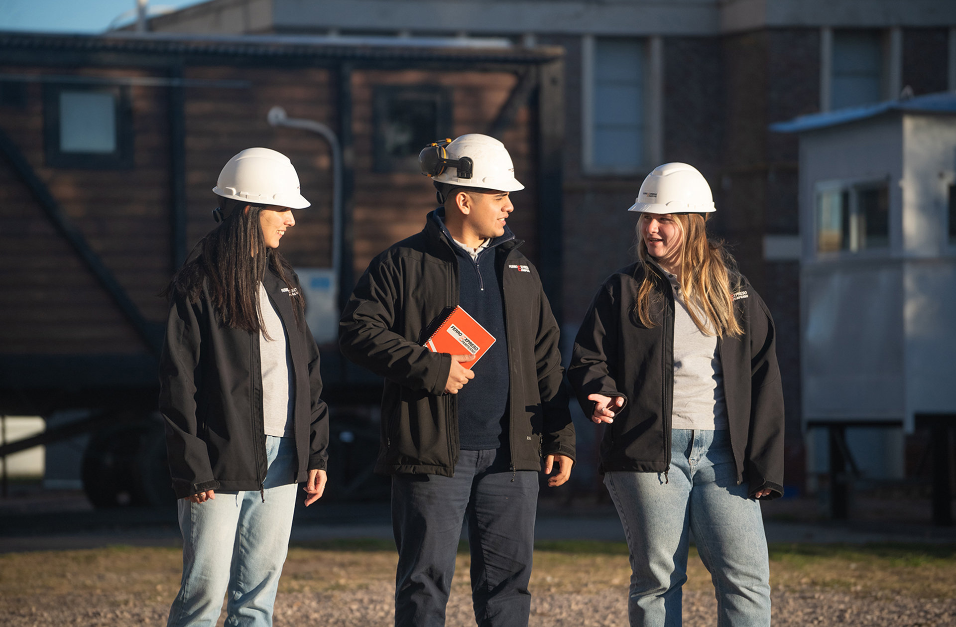 Jóvenes profesionales con cascos de seguridad participando en el programa de formación ferroviaria de Ferroexpreso Pampeano.